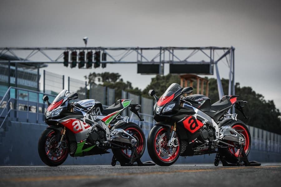 Two Aprilia superbikes on the start line of a race track